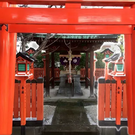 朱塗りの鳥居越しに、奥の社殿と灯籠が見える稲荷神社の全景